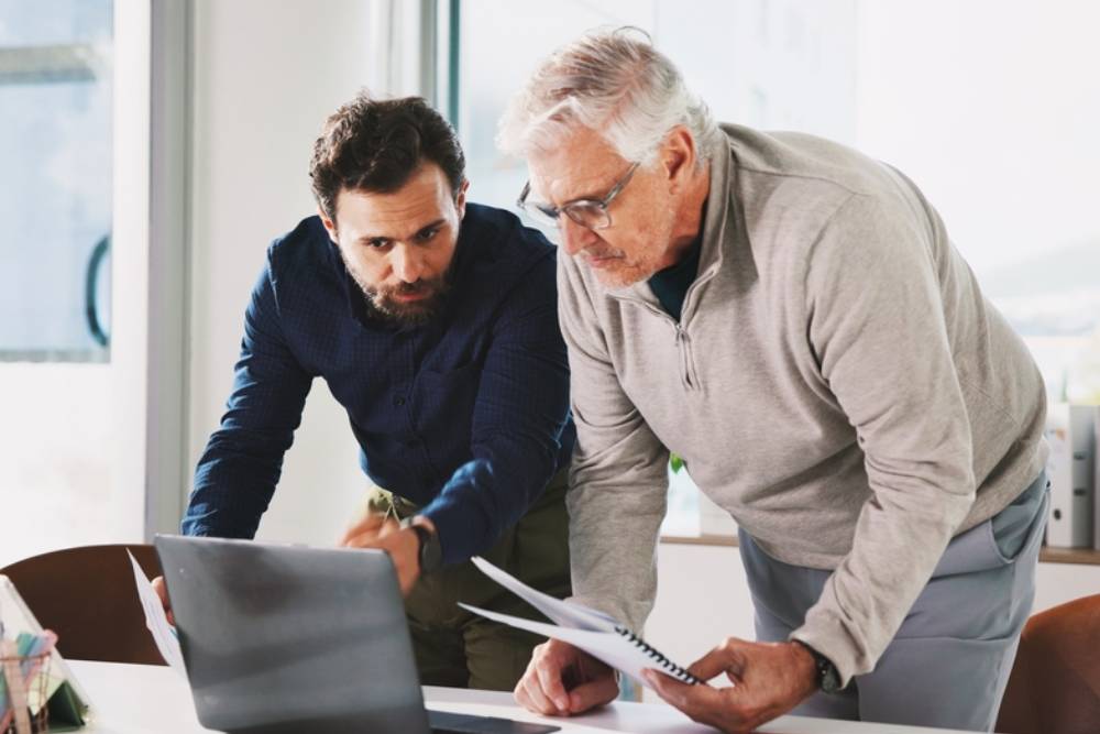 Finance, laptop and paper with business men in office for accounting or budget review.